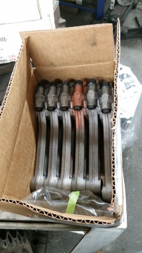 1981 Ford Bronco - A box of engine connecting rods is shown, with some parts having a copper hue.