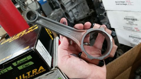 1981 Ford Bronco - A connecting rod is held in a hand, with boxes of engine parts in the background.