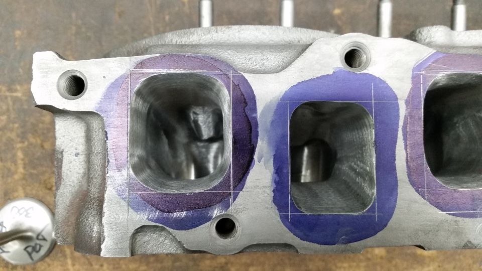 Close-up of a cylinder head with intake ports marked with purple dye and scribe lines