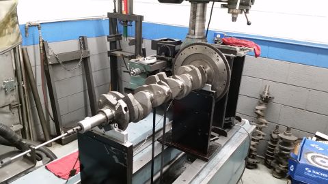 1981 Ford Bronco - A crankshaft is mounted on a balancing machine in a workshop setting.