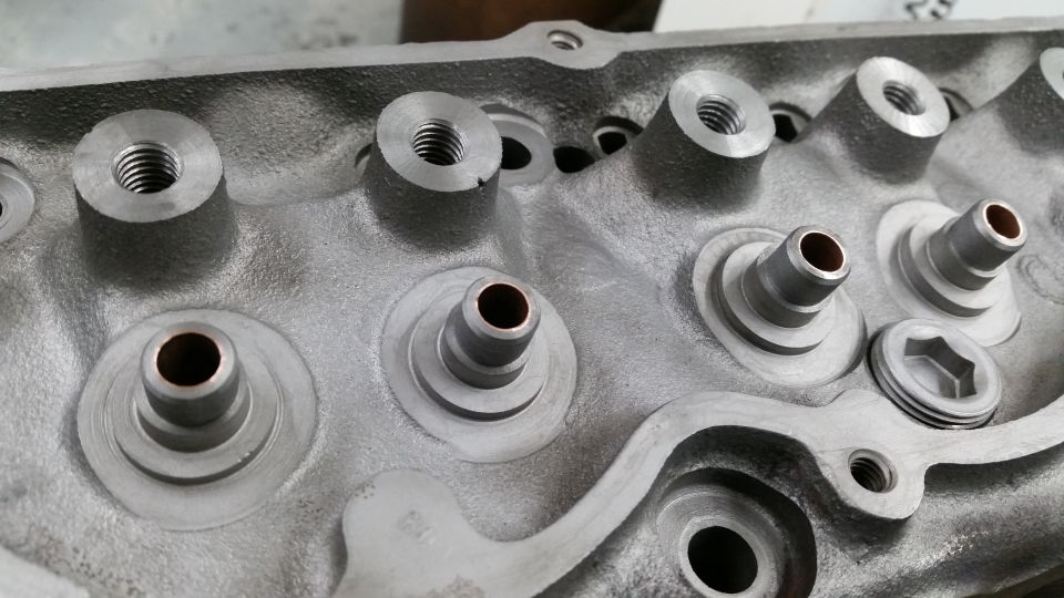 Close-up of a cast aluminum engine cylinder head with bolt holes and valve stems.