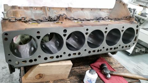 1981 Ford Bronco - A V8 engine block with six cylinders visible on the right side is secured by a chain. The engine block is resting on a wooden surface with…