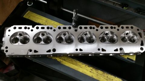 1981 Ford Bronco - A close-up, overhead view of a clean, aluminum engine cylinder head with six sets of intake and exhaust ports. The cylinder head is resting…