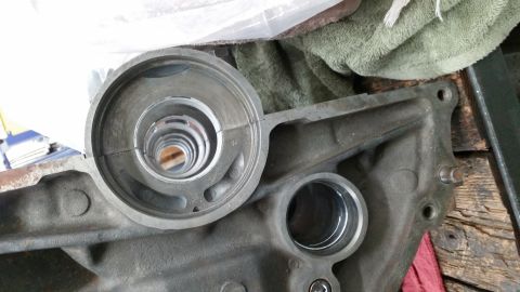 1981 Ford Bronco - A close-up view shows a cracked metal bearing cap assembly resting on a dark gray engine block. The engine block has two circular openings,…