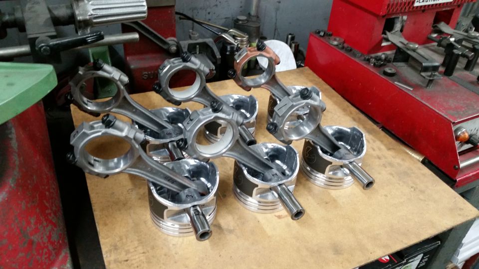Connecting rods attached to pistons in a workshop setting.