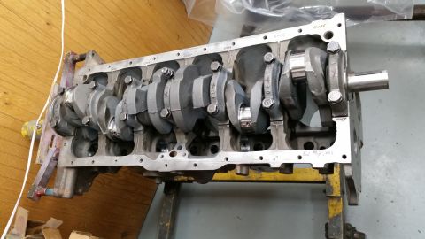 1981 Ford Bronco - A disassembled engine block with a crankshaft and connecting rods installed is shown on a yellow engine stand. The engine block is made of…