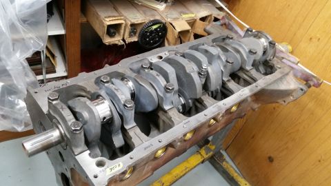 1981 Ford Bronco - A close-up view of an internal combustion engine block with a crankshaft installed. The engine block is on a yellow stand, with various mar…