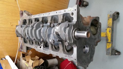 1981 Ford Bronco - A bare engine block with a crankshaft installed is shown mounted on an engine stand. The block has markings on it, including "H-026" and "E…
