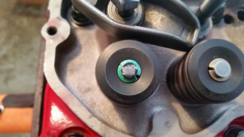 1981 Ford Bronco - A close-up view of two valve lifters on a Ford engine. The lifter in the foreground has a green seal visible around a central bolt head.