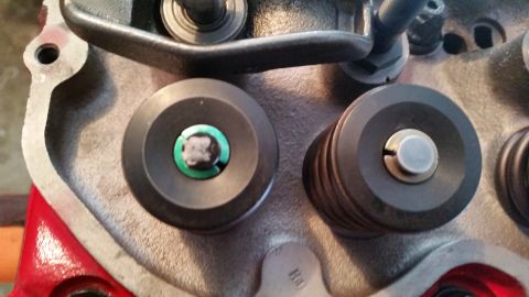 1981 Ford Bronco - A close-up view of a V8 engine's cylinder head shows two valve spring retainers with valves and keepers. The retainer on the left has a gre…