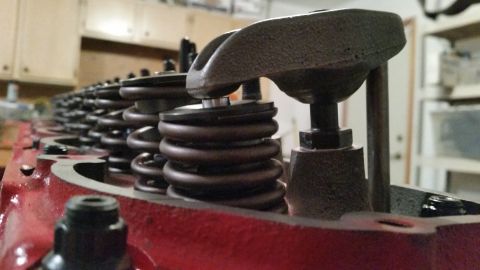 1981 Ford Bronco - Close-up view of the valve springs and rocker arms on a red V8 engine block. The engine appears to be in a workshop setting with cabinets a…