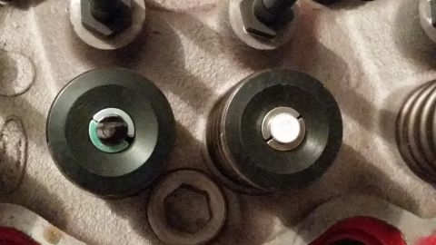 1981 Ford Bronco - A close-up view shows two black cylindrical valve spring compressors with silver inserts, positioned on a textured surface.