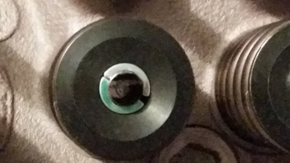 Close-up of two dark circular automotive parts, one with green and silver center detail.