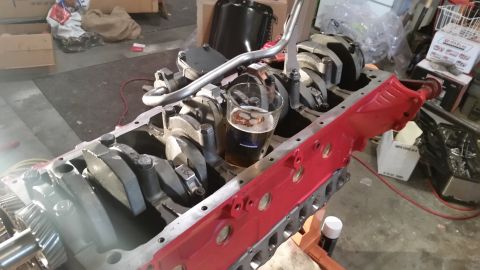 1981 Ford Bronco - A close-up view of an engine block with a glass of beer resting on the crankshaft. The engine block is partially assembled and has a red pa…