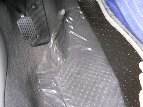 2003 Ford Taurus - Close-up of the driver's side floor area, pedals and protective plastic sheeting.