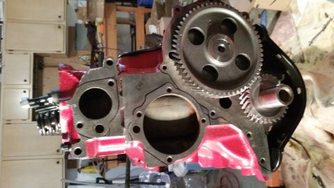1981 Ford Bronco - A close-up view of a red and silver engine block with gears attached. The engine block has a gasket outline visible around a cylinder bore.