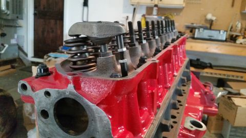 1981 Ford Bronco - A close-up view of a red V8 engine block with valve train components installed. The engine appears to be undergoing assembly or maintenance…