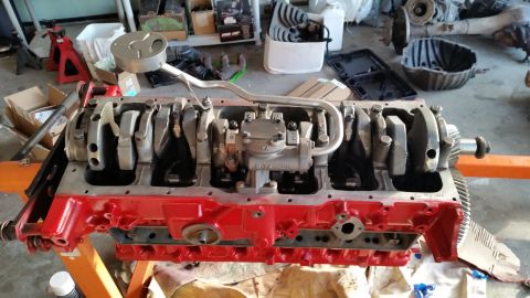 1981 Ford Bronco - A disassembled V8 engine block, painted red, is mounted on an orange engine stand. The crankshaft and connecting rods are visible inside th…