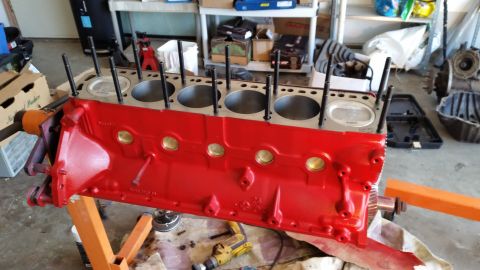 1981 Ford Bronco - A red V8 engine block is mounted on an orange engine stand. The cylinder bores are visible at the top, with several threaded studs protrudi…