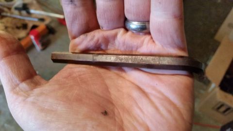 1981 Ford Bronco - A person is holding a metal hex key with "ET 8mm USA" stamped on it. The background is blurred and appears to be a workshop or garage setti…