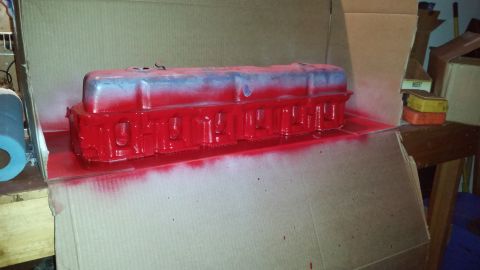 1981 Ford Bronco - A red painted valve cover is sitting inside a cardboard box, likely in the process of being restored or modified. The valve cover has a sil…