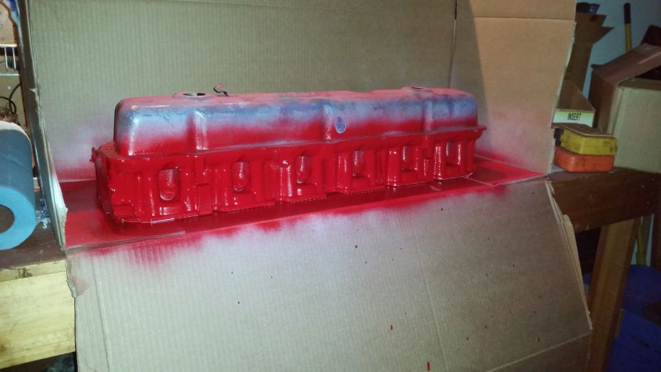 Red painted valve cover in a cardboard box.