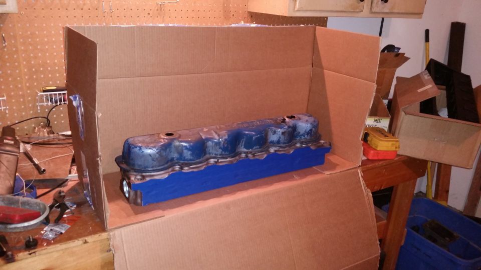 Blue engine valve cover inside a cardboard box.