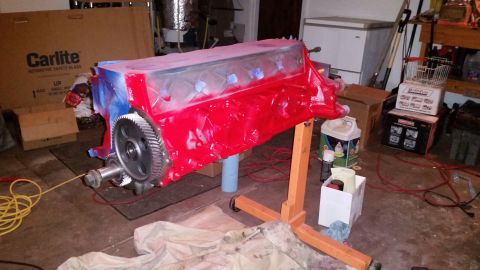 1981 Ford Bronco - A red engine block is mounted on an orange engine stand, with a large gear attached to the front. The engine block appears to be partially…