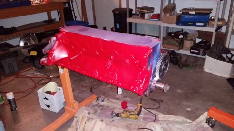 1981 Ford Bronco - A red painted engine block is mounted on an orange engine stand, with a large gear attached to one end. The engine bay appears to be in a g…