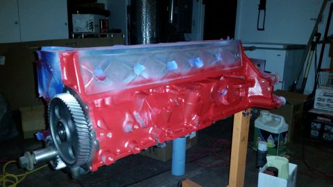 1981 Ford Bronco - A red engine block is displayed on a stand, partially covered in blue masking tape and plastic sheeting. A large metal gear is attached to…
