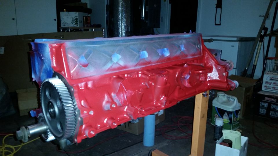 Red engine block with a large gear on a stand, partially masked.