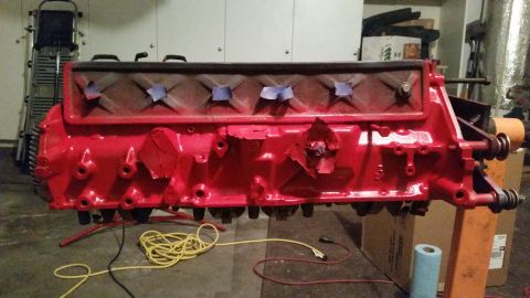 1981 Ford Bronco - A bright red engine block is mounted on an engine stand, with some areas taped off. The engine appears to be in a garage or workshop settin…