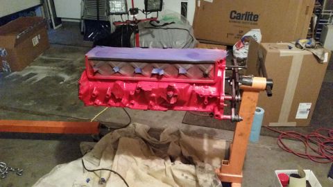1981 Ford Bronco - A red engine block is mounted on an orange engine stand in a garage setting. The top of the engine block is covered with purple material an…