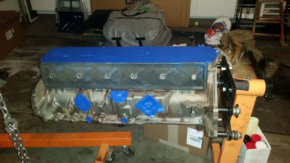 V8 engine block on an engine stand with blue tape on the valve cover.