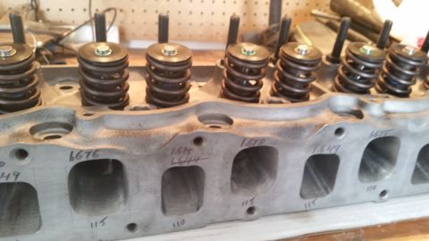 1981 Ford Bronco - A close-up view of a V8 engine cylinder head with valve springs and retainers installed. Numbers are written in marker on the exhaust ports…