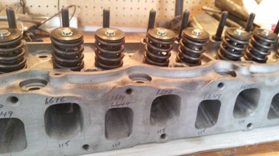 Close-up of a V8 engine cylinder head with valve springs and marked exhaust ports.