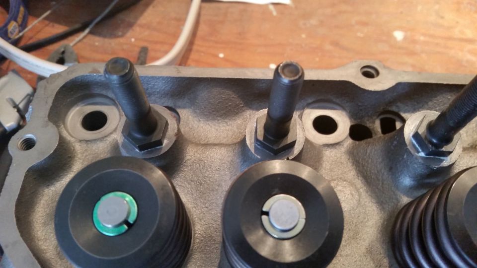 Close-up of engine cylinder head with valve spring retainers and rocker arm studs.