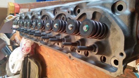 1981 Ford Bronco - A close-up, angled view of a cast iron engine cylinder head with multiple valve springs and retainers visible. The engine part is resting o…