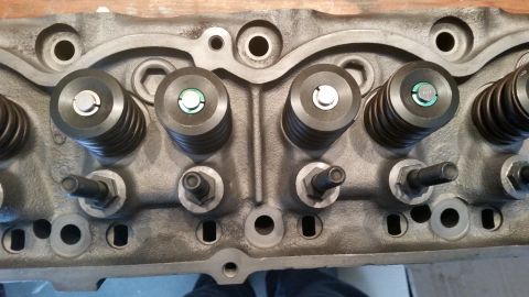 1981 Ford Bronco - A close-up, overhead view of a cast iron engine cylinder head with multiple valves and valve springs installed. Several rocker arms and adj…
