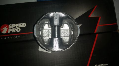 1981 Ford Bronco - A close-up, overhead view of a new, silver piston sits on top of black boxes with red accents and the "SPEED PRO SYSTEMS" logo. The piston…