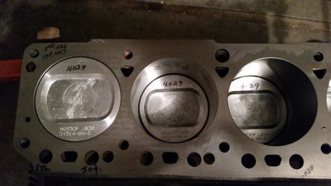 1981 Ford Bronco - A close-up view of a Ford engine block with three pistons installed. Handwritten markings are visible on the block and pistons, including n…