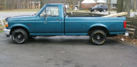 1996 Ford F-150 - A teal pickup truck is parked on a paved surface, viewed from the side.