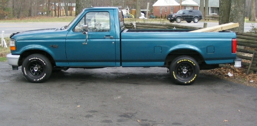 Teal pickup truck, side view, with black wheels and white-letter tires