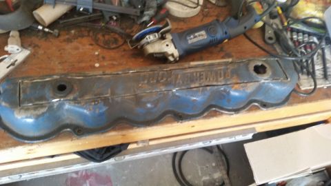 1981 Ford Bronco - A blue valve cover with visible text sits on a workbench next to an angle grinder.