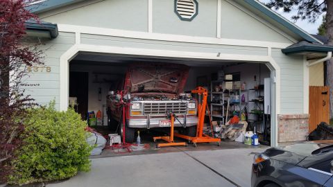 1981 Ford Bronco - A red Ford truck is parked in a garage with its hood open, undergoing maintenance.