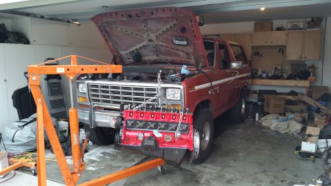 1981 Ford Bronco - A red Ford Bronco is in a garage with its hood up and engine being removed.