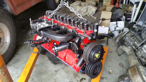 1981 Ford Bronco - Engine assembly suspended by chains on an engine stand in a garage setting.