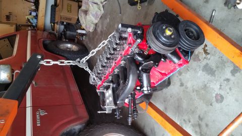 1981 Ford Bronco - An engine is hoisted out of a red vehicle, likely a Ford Bronco, in a garage setting.