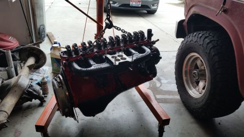 1981 Ford Bronco - Engine being worked on next to a truck and spare axle in a garage.