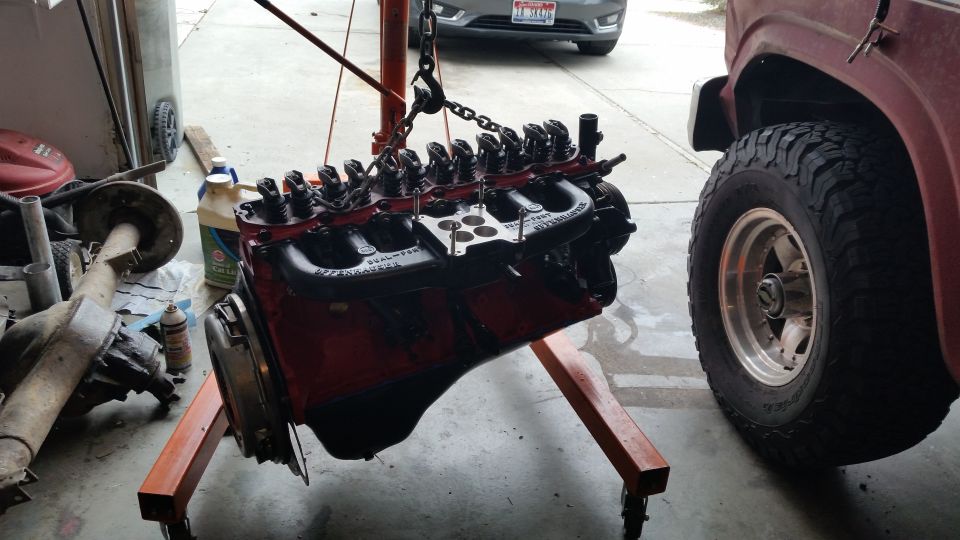 Engine on stand, rear axle, and side of a red truck with large tires